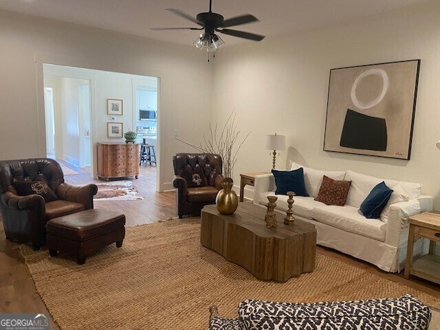 living area with a ceiling fan and wood finished floors