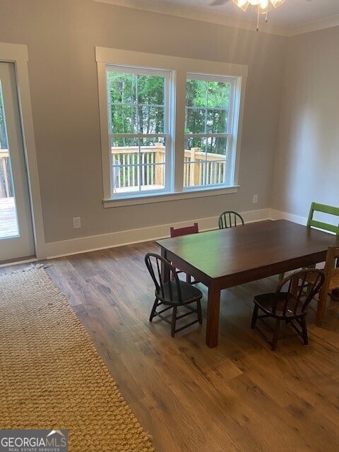 dining space with crown molding, baseboards, and wood finished floors