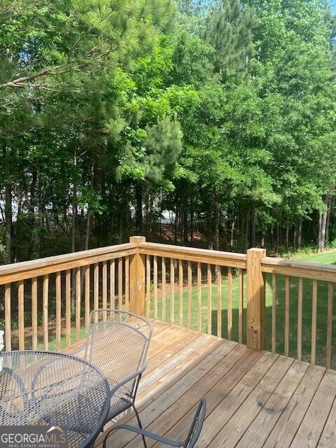 wooden deck featuring a lawn and outdoor dining area