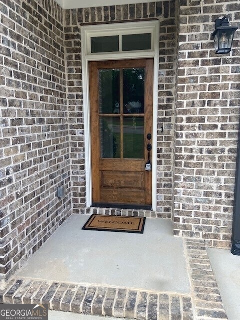 view of exterior entry featuring brick siding