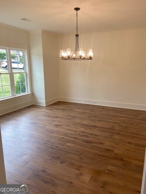 empty room with an inviting chandelier, baseboards, and dark wood-style floors