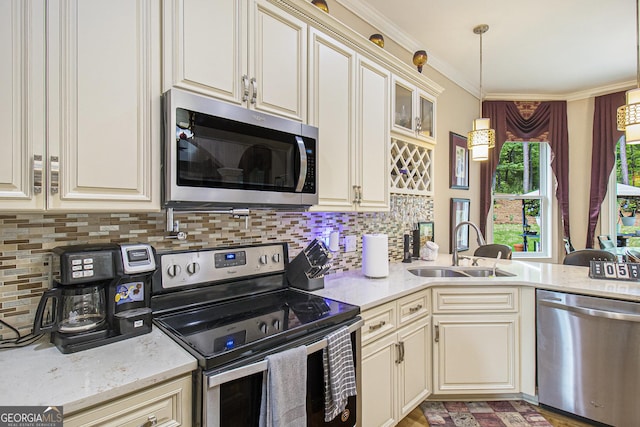 kitchen with a sink, appliances with stainless steel finishes, backsplash, and hanging light fixtures