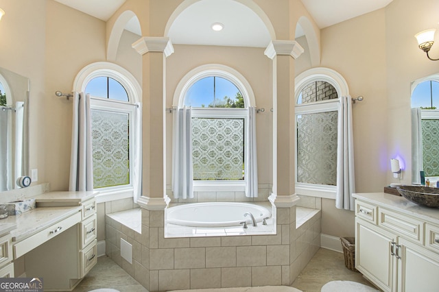 full bath featuring vanity, decorative columns, a bath, and a wealth of natural light