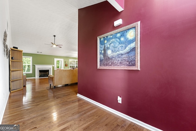1395 Brisbane Dr, Dacula, GA 30019 - unfurnished living room featuring baseboards, wood finished floors, a fireplace with flush hearth, and ceiling fan