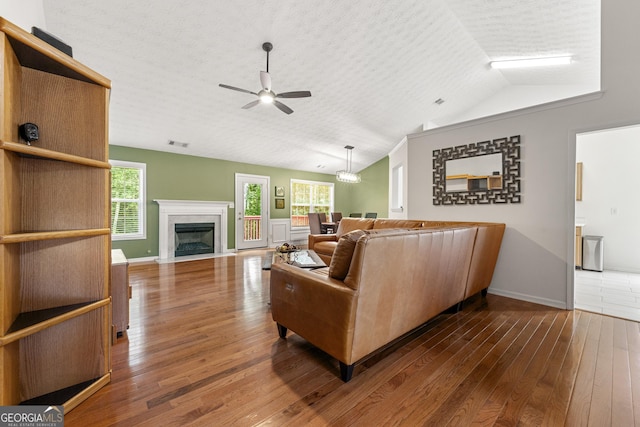 1395 Brisbane Dr, Dacula, GA 30019 - living room featuring a ceiling fan, hardwood / wood-style flooring, vaulted ceiling, a fireplace with flush hearth, and baseboards