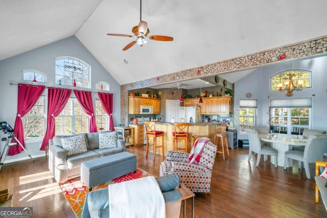 living area featuring high vaulted ceiling, ceiling fan with notable chandelier, and dark wood finished floors