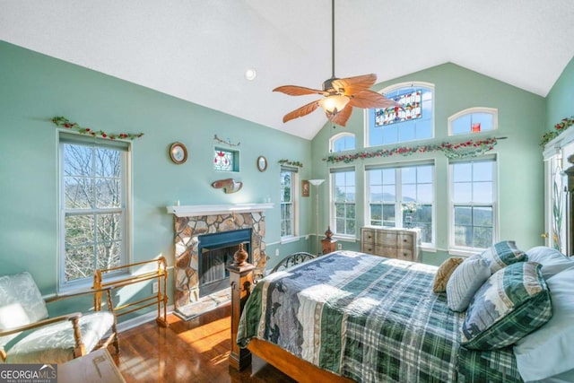 bedroom with a stone fireplace, wood finished floors, vaulted ceiling, and multiple windows
