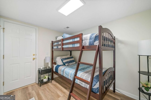 bedroom featuring baseboards, visible vents, and wood finished floors