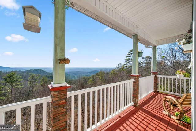 deck featuring covered porch and a wooded view