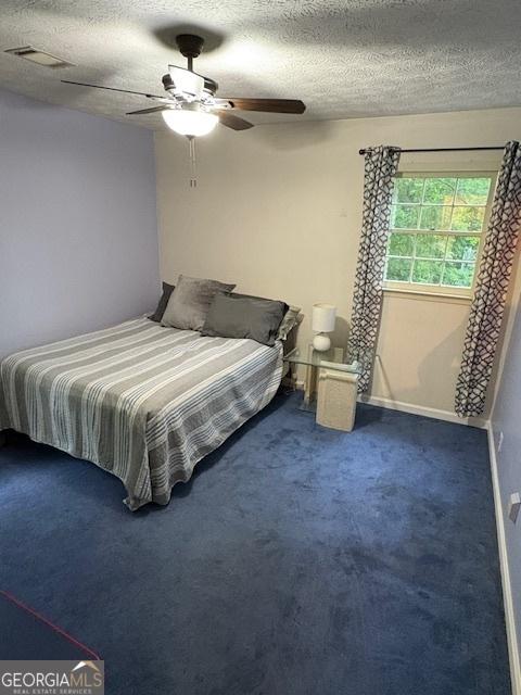 carpeted bedroom with a textured ceiling, ceiling fan, and baseboards