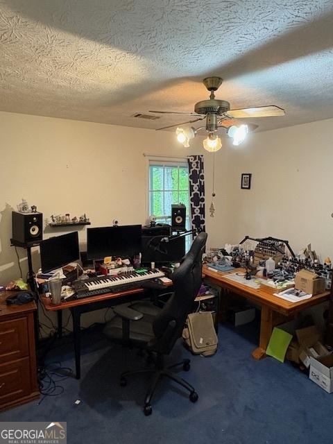 carpeted home office with a ceiling fan and a textured ceiling