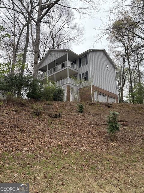 back of house with an attached garage and a balcony