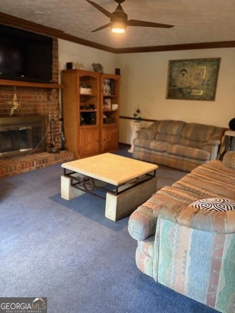 living room featuring carpet floors, a ceiling fan, ornamental molding, a brick fireplace, and a textured ceiling