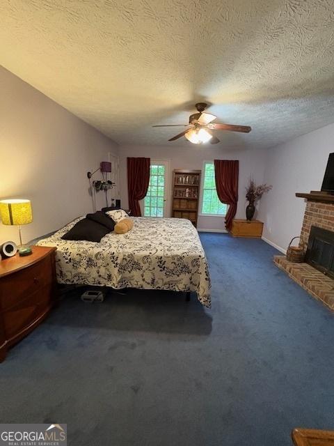 bedroom with carpet floors, a fireplace, a textured ceiling, and ceiling fan