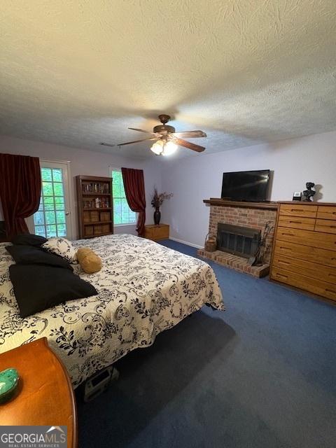 carpeted bedroom featuring a fireplace, a textured ceiling, and a ceiling fan