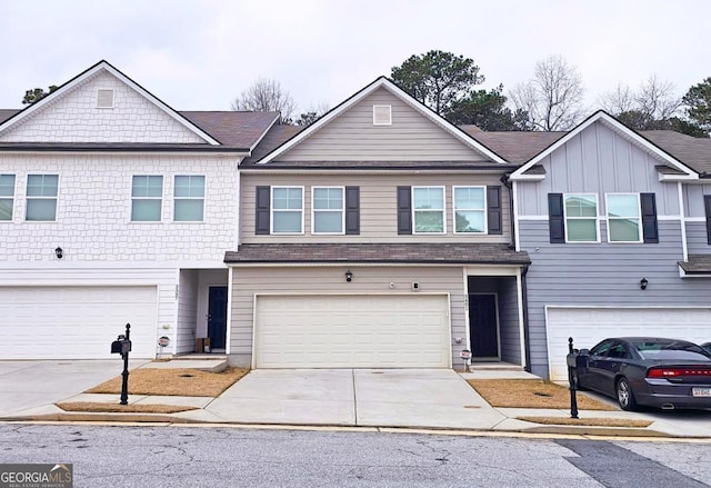 view of property featuring a garage, driveway, and a shingled roof