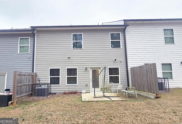 rear view of property featuring a patio, a lawn, and fence