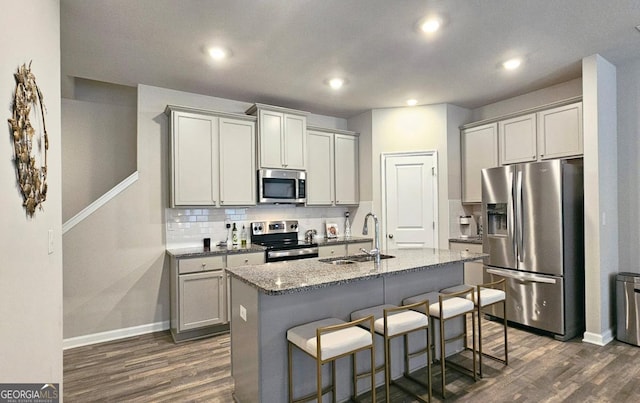 kitchen featuring baseboards, a sink, dark wood-style flooring, and stainless steel appliances
