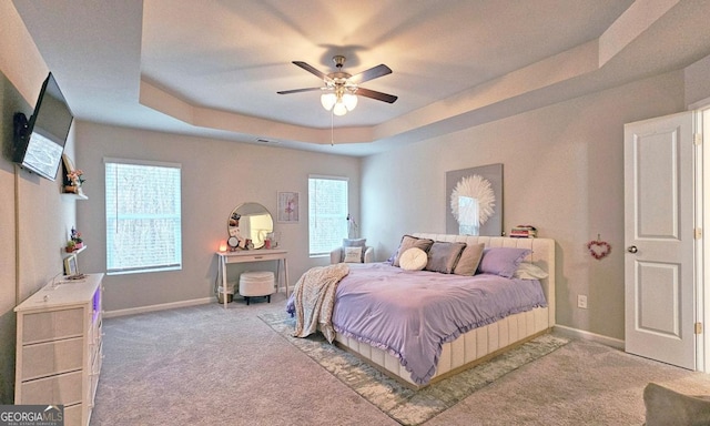 bedroom featuring carpet flooring, ceiling fan, baseboards, a tray ceiling, and visible vents