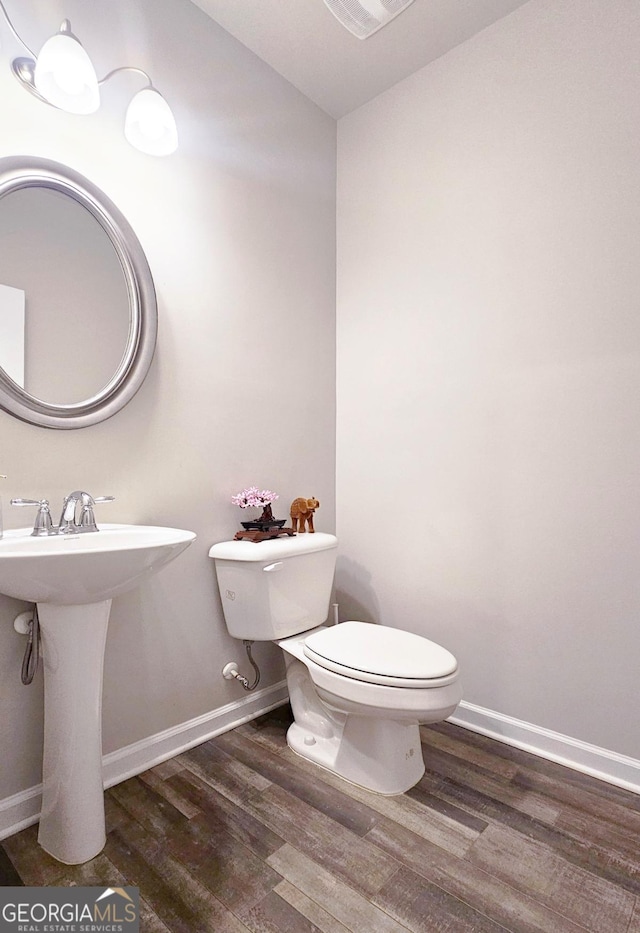 bathroom featuring baseboards, wood finished floors, and toilet
