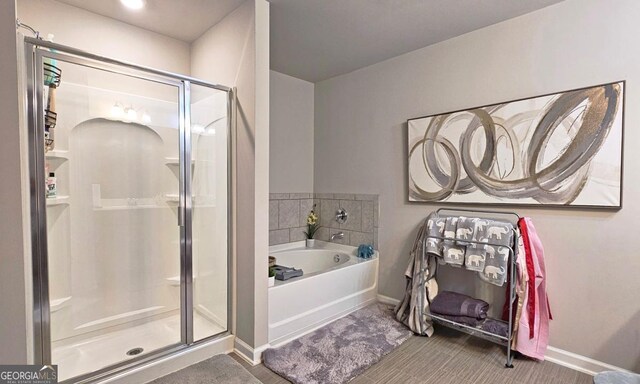 full bath with baseboards, a garden tub, and a stall shower