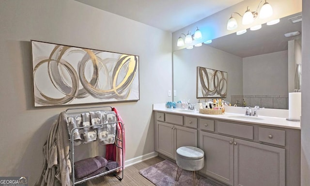 bathroom featuring a sink, baseboards, double vanity, and wood finished floors