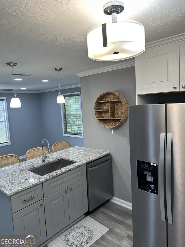 kitchen featuring a sink, appliances with stainless steel finishes, light wood-type flooring, and a textured ceiling