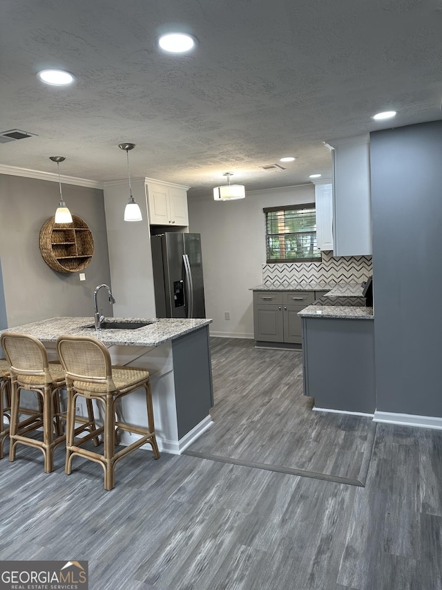 kitchen with visible vents, dark wood-type flooring, and stainless steel fridge with ice dispenser