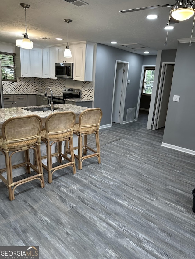 kitchen with visible vents, a sink, appliances with stainless steel finishes, and wood finished floors