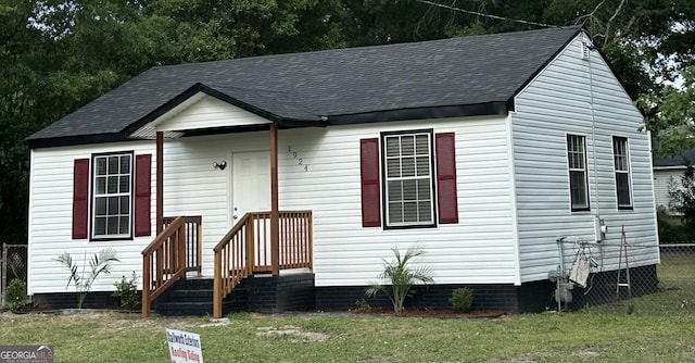 view of front of home featuring fence, a shingled roof, and a front yard
