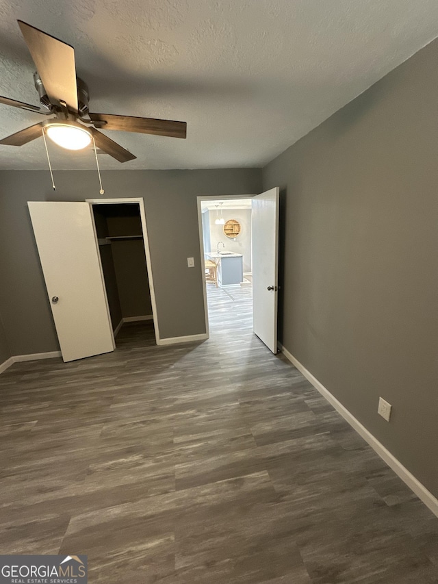 unfurnished bedroom featuring a closet, wood finished floors, baseboards, ceiling fan, and a sink