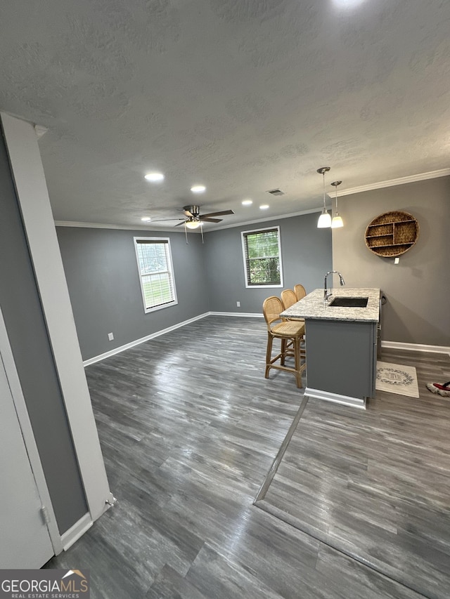 interior space featuring ceiling fan, decorative light fixtures, a sink, baseboards, and ornamental molding