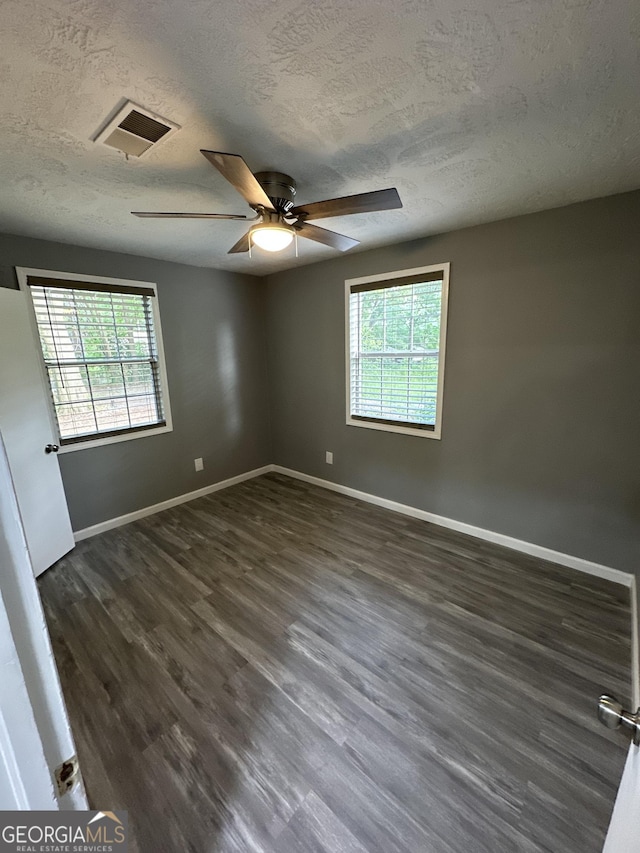 empty room featuring a textured ceiling, plenty of natural light, and baseboards