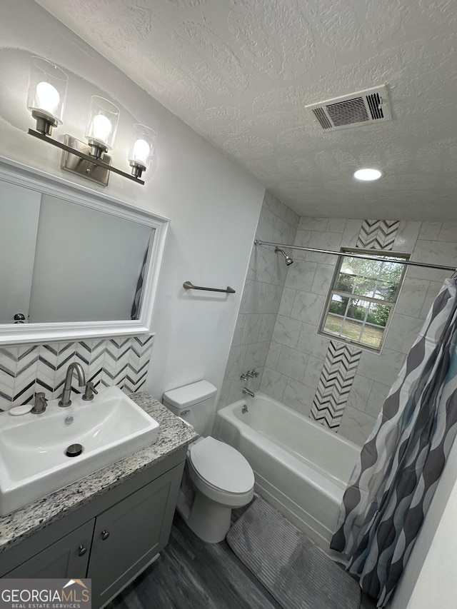 full bathroom with toilet, a textured ceiling, visible vents, and wood finished floors