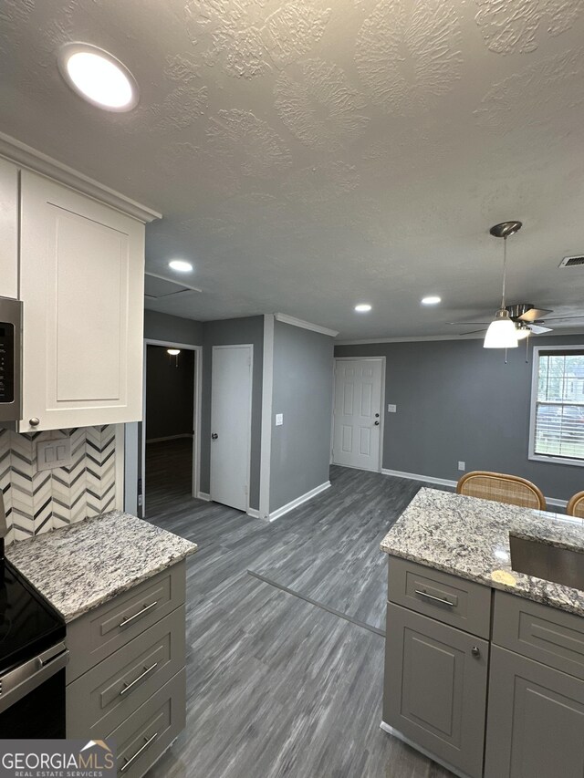 kitchen featuring electric range oven, baseboards, decorative backsplash, dark wood-type flooring, and gray cabinetry