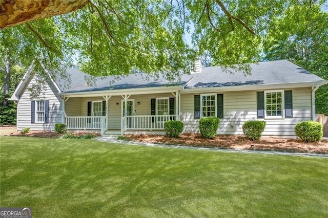 ranch-style home with a porch, a chimney, and a front yard