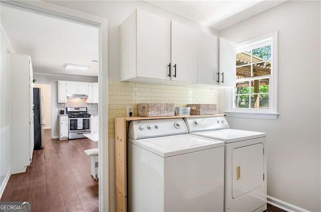 clothes washing area featuring separate washer and dryer, dark wood finished floors, cabinet space, and baseboards
