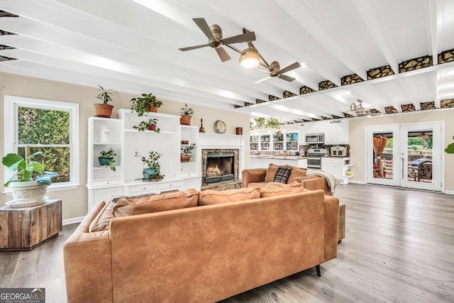 701 Mask Rd, Brooks, GA 30205 - living area featuring light wood-style floors, a lit fireplace, a ceiling fan, and beam ceiling