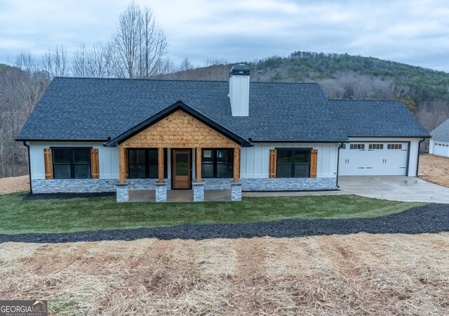 view of front of property with a shingled roof, a chimney, an attached garage, and driveway