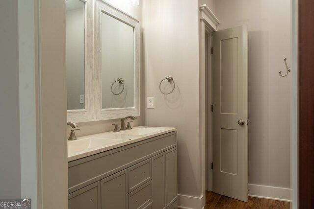 full bathroom featuring double vanity, a sink, baseboards, and wood finished floors