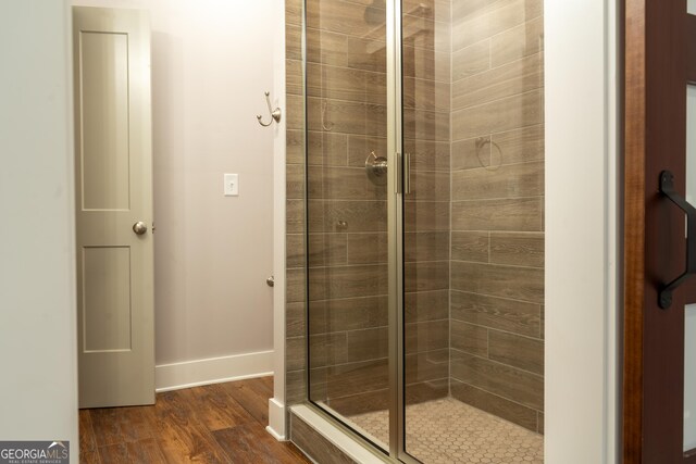 bathroom featuring baseboards, wood finished floors, and a shower stall