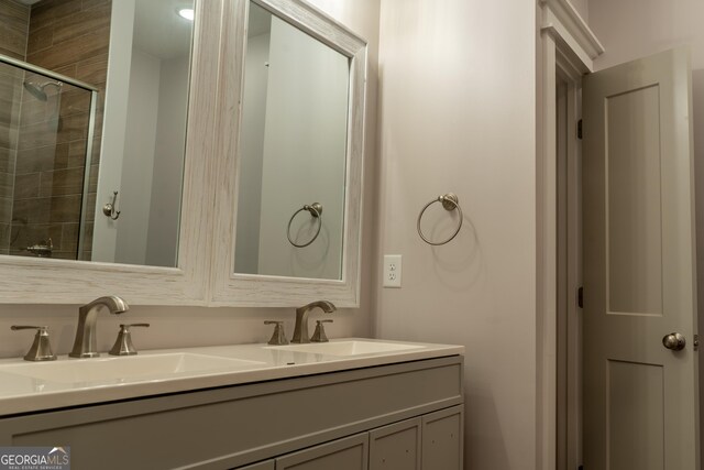 bathroom with a sink, a tile shower, and double vanity