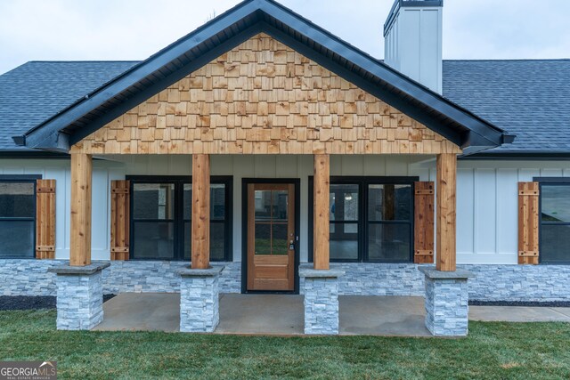 exterior space with board and batten siding, a shingled roof, stone siding, and a chimney