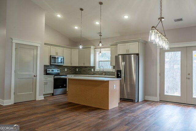 kitchen featuring dark wood-style flooring, stainless steel appliances, backsplash, visible vents, and a kitchen island