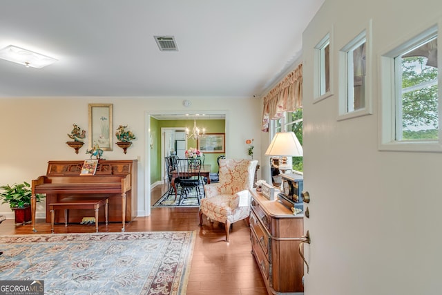 sitting room featuring visible vents, plenty of natural light, wood finished floors, and a notable chandelier
