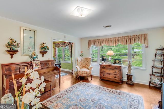 living area featuring crown molding, baseboards, hardwood / wood-style floors, and visible vents