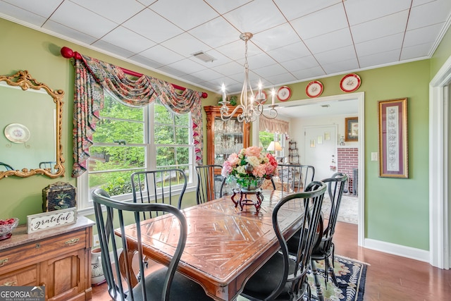 dining room featuring a chandelier, baseboards, light wood-type flooring, visible vents, and ornamental molding