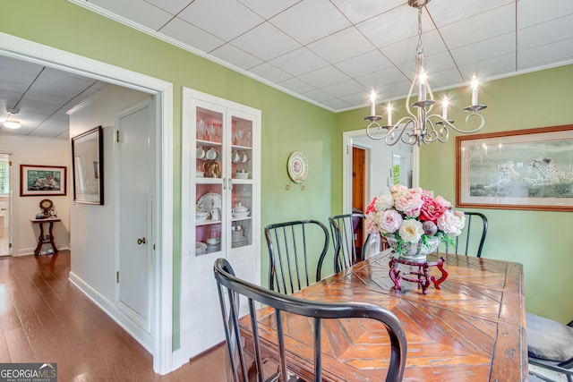 dining space featuring ornamental molding, wood finished floors, and a chandelier