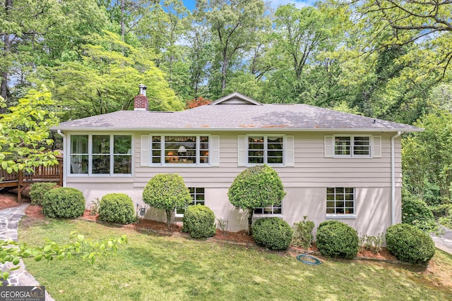 exterior space with a chimney, a shingled roof, and a front yard