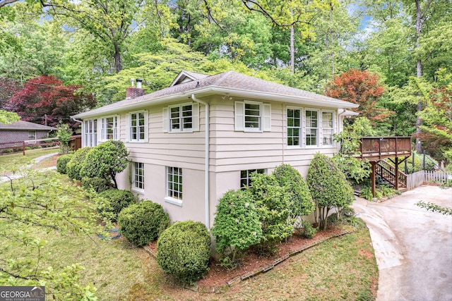 view of side of home featuring stairs, a wooden deck, stucco siding, and a chimney